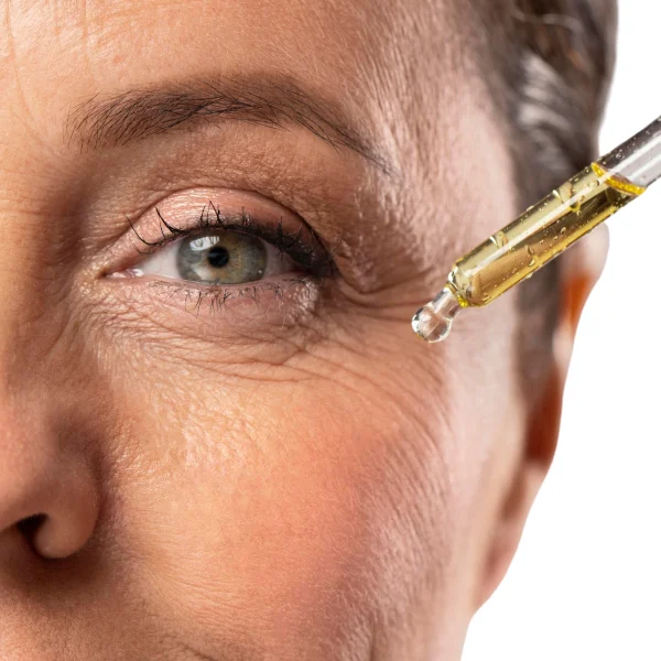 A woman applying eye drops with a dropper, focusing intently on her eye.