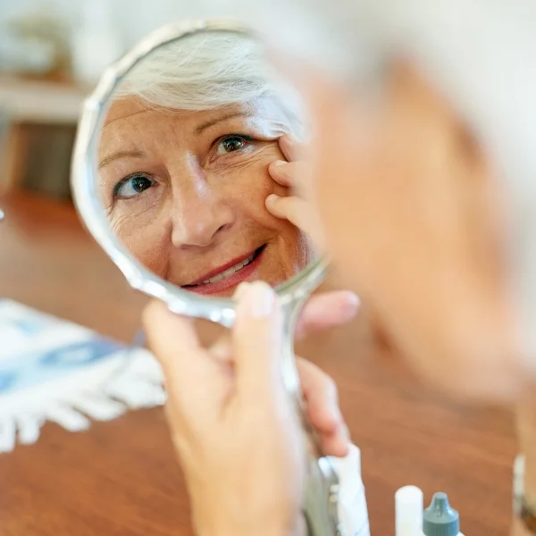 Femme regardant dans un miroir, les yeux fermés, exprimant la réflexion et la contemplation intérieure.