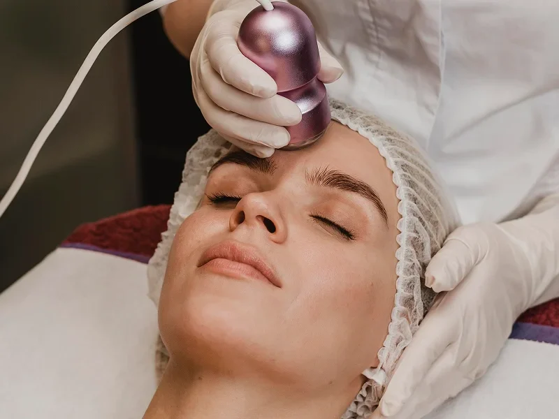 A woman receiving a facial radiofrequency treatment with a specialized device on her face.