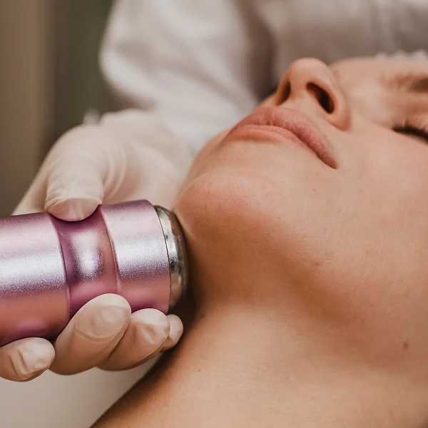 A woman receiving a facial radiofrequency treatment using a purple device, focused on her skin rejuvenation.