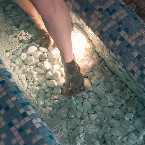 A person standing in a thermal spa tub filled with water, enjoying a relaxing experience.