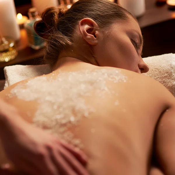 A woman receiving a back massage in a serene hammam spa setting, surrounded by warm, calming colors and soft lighting.