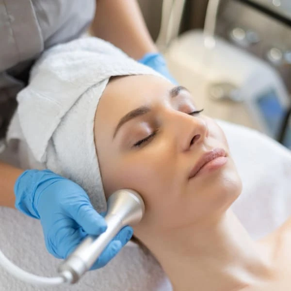 A woman receiving a facial treatment in a serene spa environment, with soothing products applied to her face.