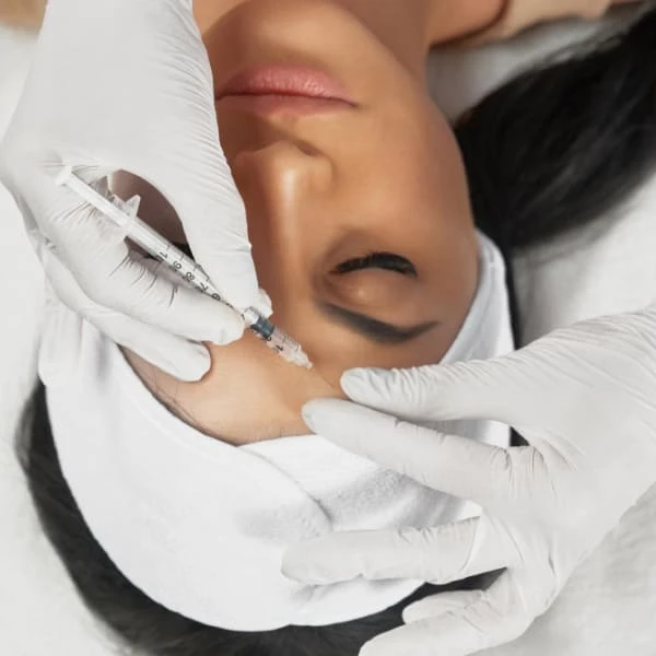 Une femme reçoit une injection faciale dans un cadre médical.