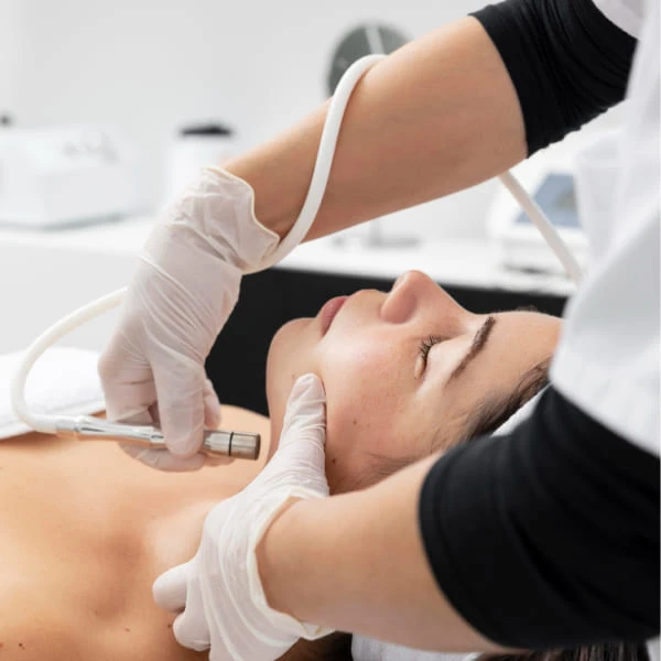A woman receiving a facial treatment in a spa setting, relaxing with a mask applied to her face.